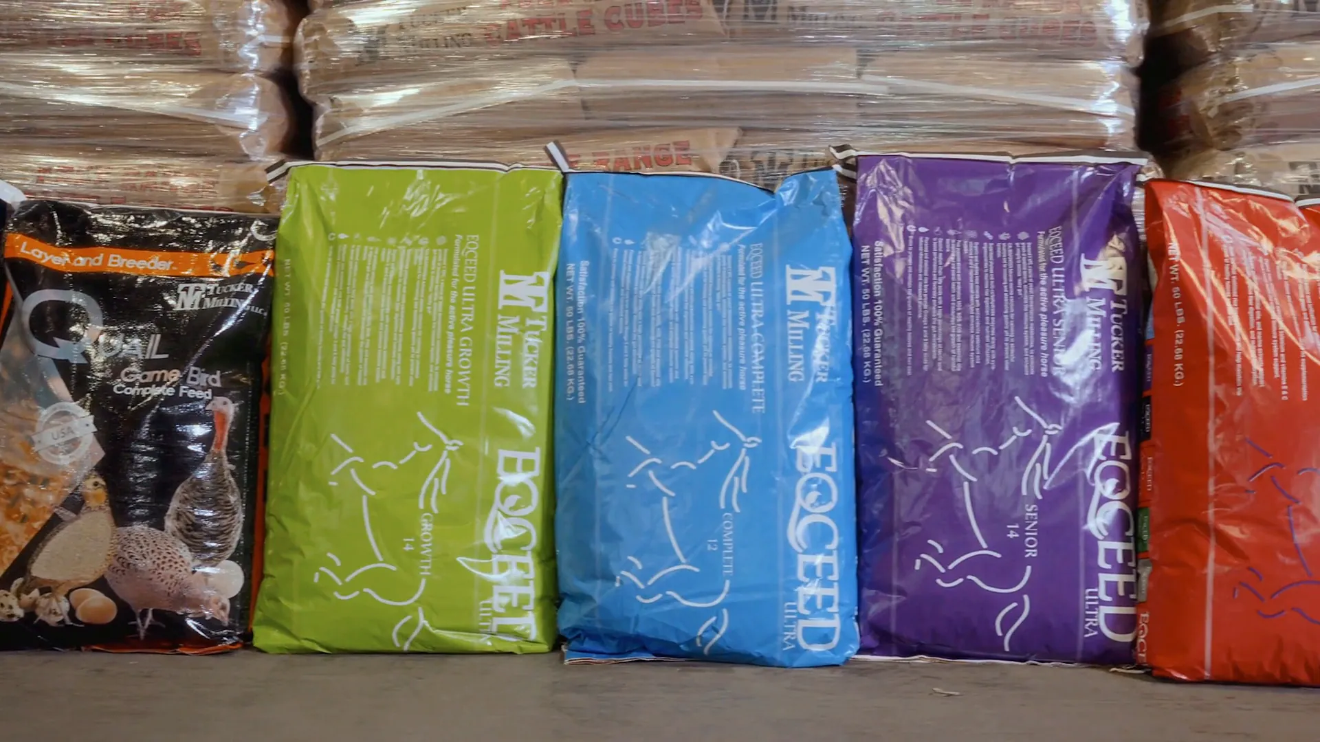Finished bags of Tucker Milling feed, Quail and Game Bird and Eqceed, in front of wrapped pallets